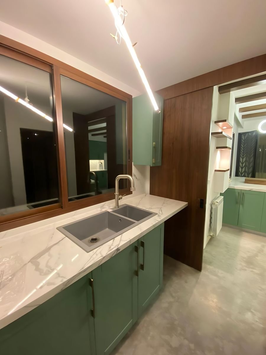 Sage kitchen with a walnut-framed opening